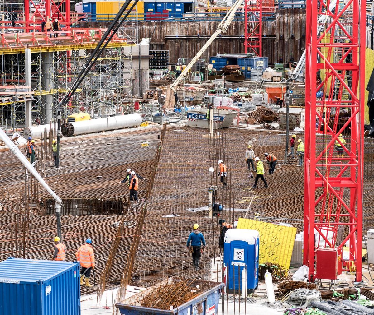 Große Baustelle mit Kran, Bewehrung und Bauarbeitern