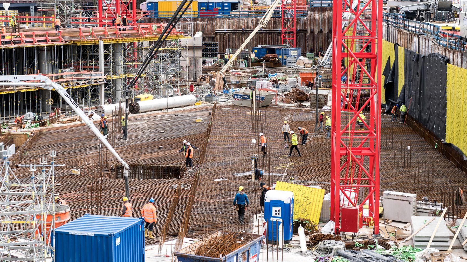 Große Baustelle mit Kran, Bewehrung und Bauarbeitern